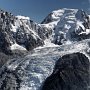 The Chamonix Aiguilles are bathed in sun while storms rage higher on Mont Blanc's summit
